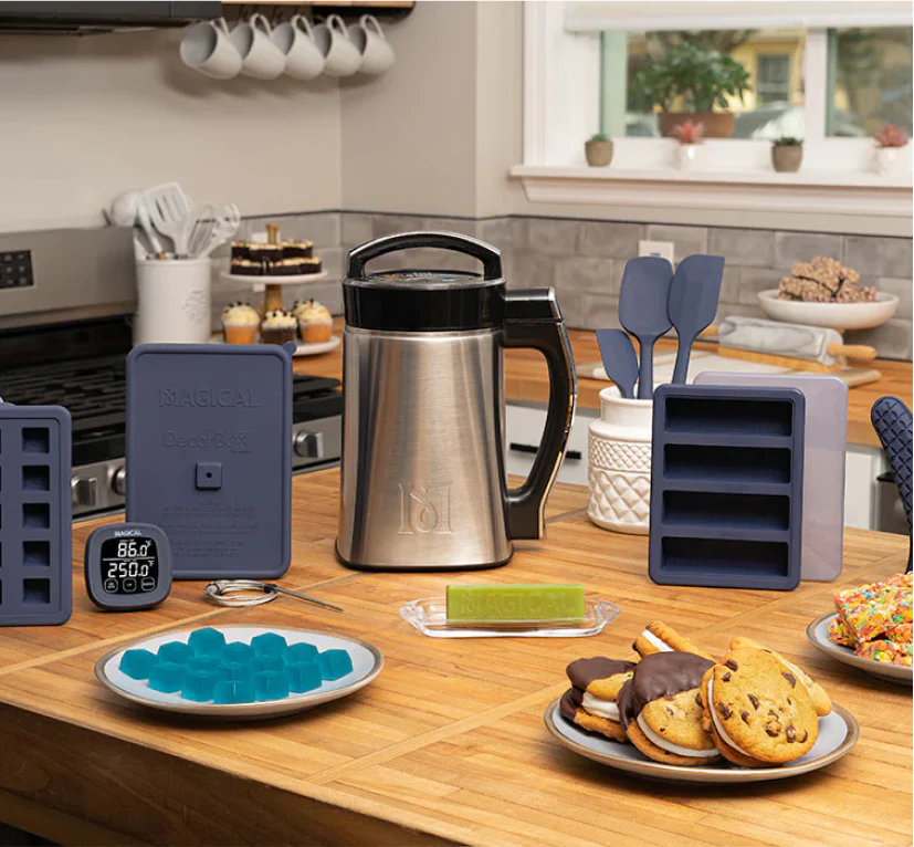 A variety of finished products, including a jar of herb-infused oil, a small bottle of flavored syrup, and a container of herbal balm, showcasing the machine's versatility.